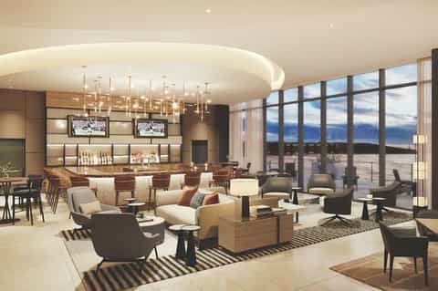 Upscale resort bar and lounge with modern pendant lights, ocean view windows, and seating