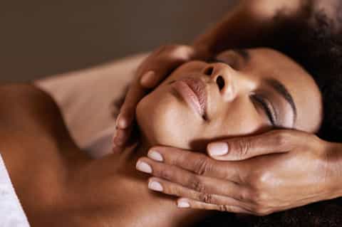 Close-up of spa massage with therapist's hands on client's face and shoulders