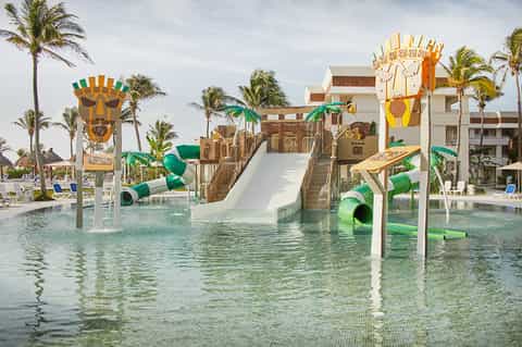 Tropical water park with Egyptian-themed structures, waterslides, and palm trees at all-inclusive resort