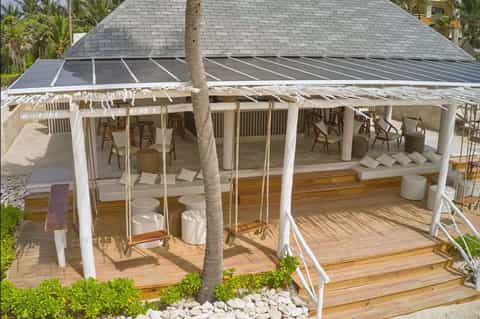 Covered patio with white pergola, loungers, and ocean view