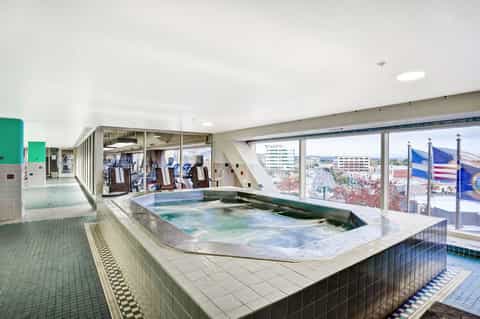 Indoor hot spring pool with colorful water and city views through large windows