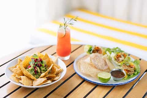 Beachside dining with nachos, fish tacos, and coral-colored cocktail
