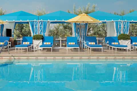 Resort pool with blue and yellow cabanas, lounge chairs, and tent-style seating structures