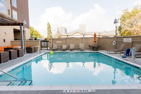 Urban rooftop pool with lounge chairs and city skyline views