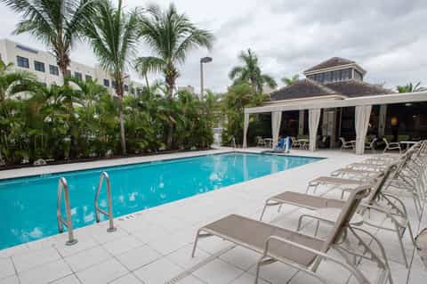 Rectangular pool with covered cabana, lounge chairs, and tropical landscaping