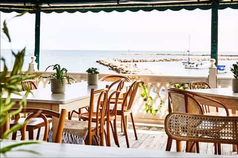 Beachfront restaurant with green awning overlooking harbor and boats