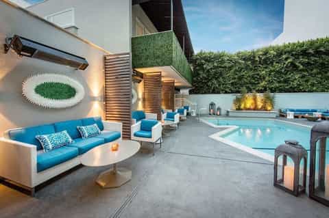 Modern pool deck at twilight with blue loungers, lounge seating, and landscaping