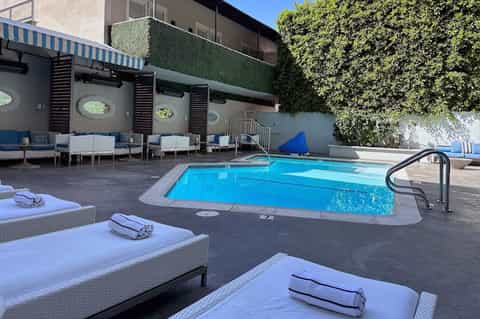 Resort pool with white lounge chairs, ivy-covered walls, and contemporary architectural design