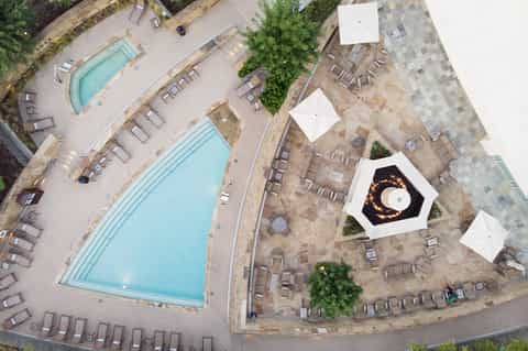 Aerial view of resort pools, loungers, umbrellas, and surrounding grounds