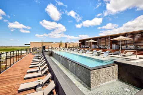 Modern rooftop pool with contemporary architecture, loungers, and umbrella shade structures