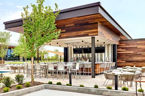 Contemporary outdoor pavilion with wooden ceiling, dining area, and lounge seating by pool