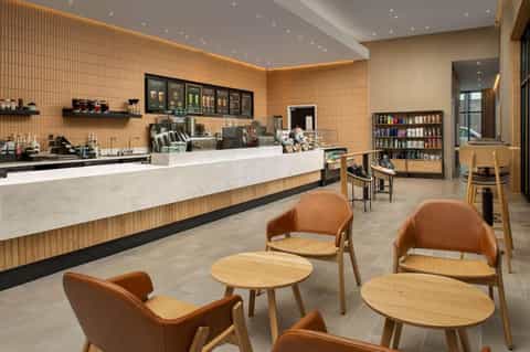 Bright café space with wood-paneled walls, white counter, brown leather chairs, and retail shelving