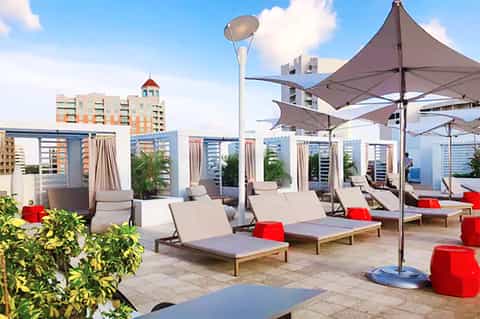 Rooftop pool deck with loungers, umbrellas, and city skyline views