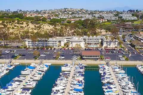 Aerial view of waterfront development with marina, parking lot, and hillside homes