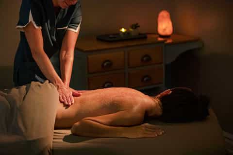 Professional massage therapist providing treatment in candlelit spa room