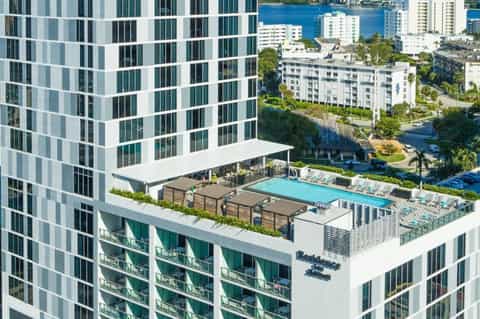 Aerial view of rooftop pool and lounge area in high-rise urban residential building