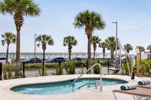 Beachfront spa hot tub with palm trees, railings, and waterfront views