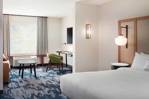 Contemporary hotel guest room with bed, work desk, and floor-to-ceiling window