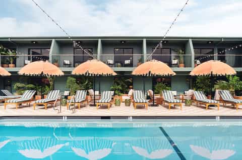 Resort pool with striped loungers, orange umbrellas, and modern building