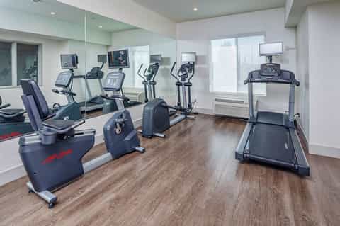 Modern fitness center with cardio equipment, exercise bikes, treadmill, and mirrored walls