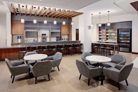 Modern hotel lounge with bar, seating areas, and beverage station