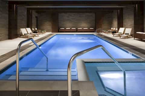 Indoor swimming pool with multiple lounge chairs and spa facilities in contemporary design space