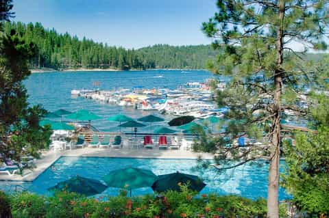 Mountain lake resort pool with forest views and umbrella seating areas