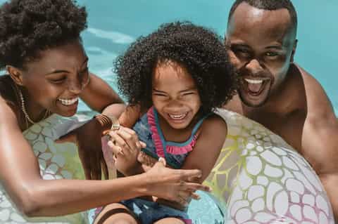 Family enjoying time in ocean water, smiling and playing together on a sunny beach day
