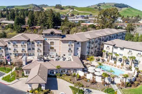 Hillside Hyatt House hotel exterior with multi-story buildings and resort pool amenities