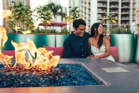 Couple by fire pit with flames in urban rooftop lounge setting