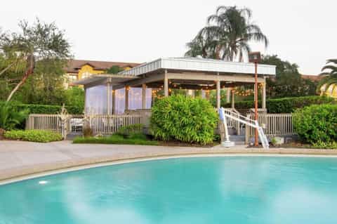 Resort pool at dusk with covered cabana, palm trees, and string lights
