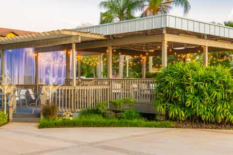 Covered resort patio with string lights, lounge chairs, views of palm trees and tropical vegetation