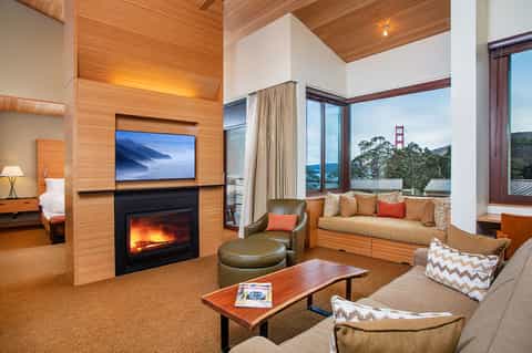 Hotel suite with fireplace, flat-screen TV, wood ceiling, bay window seating overlooking Golden Gate Bridge