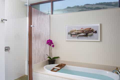 Luxury bathroom with soaking tub, rainfall shower, and scenic hillside window view
