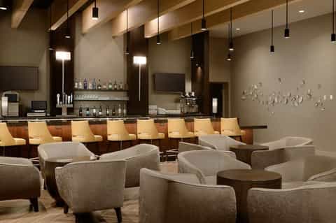Upscale hotel lounge with bar seating, modern furniture, and ambient lighting