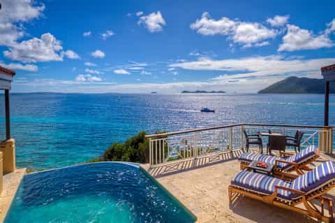 Private infinity pool on oceanfront terrace with striped lounge chairs and panoramic tropical water views