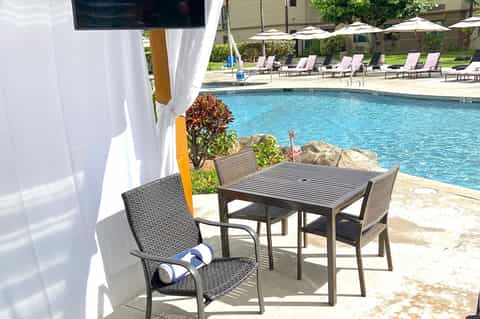 Poolside patio with shaded dining area, lounge chairs, and crystal-blue swimming pool
