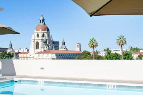 Rooftop pool with city skyline view featuring historic dome building and palm trees
