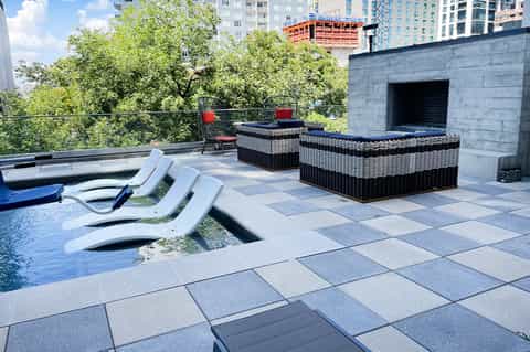 Urban rooftop pool deck with modern lounge chairs and city skyline views