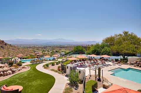 Desert resort pools, loungers, and mountain views under clear blue sky