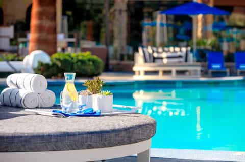 Poolside table with rolled towels, water bottle, and succulent plant by blue pool
