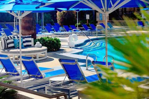 Luxury pool area with blue loungers, white umbrellas, and vibrant blue water feature
