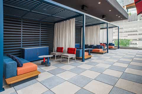 Contemporary rooftop terrace with striped privacy panels, colorful furniture, and urban backdrop