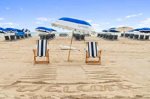 Beach chairs and umbrellas on sandy beach with striped loungers and blue parasols
