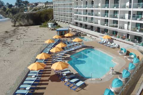 Beachfront resort pool with yellow umbrellas and loungers, sandy beach adjacent