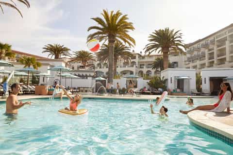 Family-friendly resort pool with palm trees, cabanas, and shallow areas
