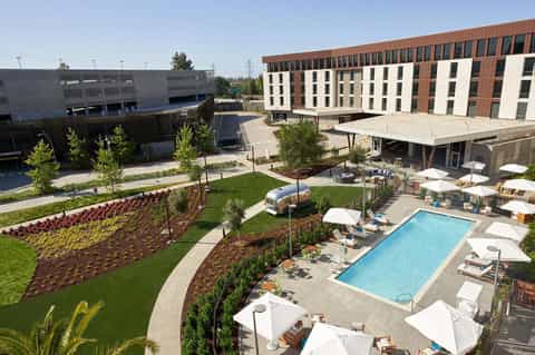 Aerial view of modern resort courtyard with rectangular pool, lounge chairs, and landscaped grounds
