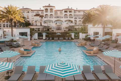 Mediterranean-style resort pool with striped umbrellas and elegant architecture
