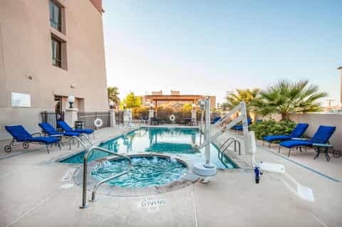 Rooftop pool and hot tub area with blue loungers and city skyline views