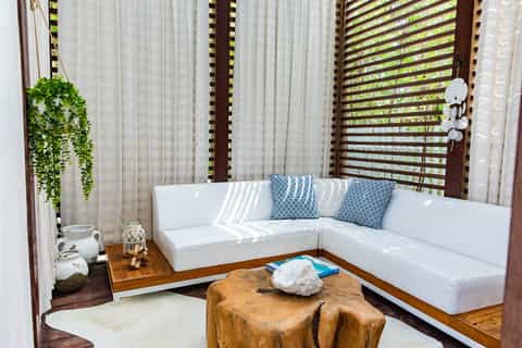 Contemporary outdoor lounge with white sectional, wooden accent table, and green lattice screens